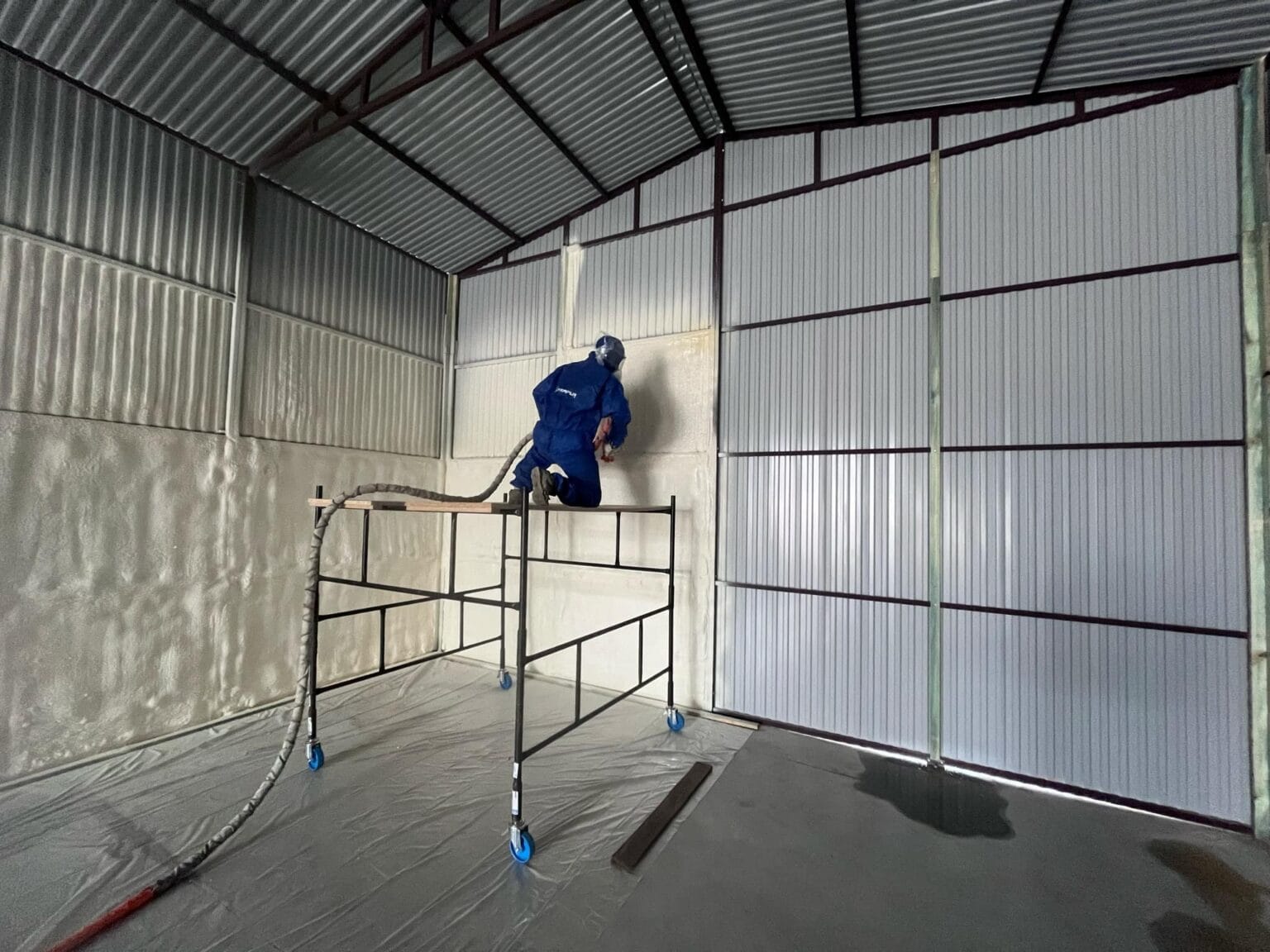 Aplikator pianki PUR, nakłada izolacje natryskową na halę przemysłową